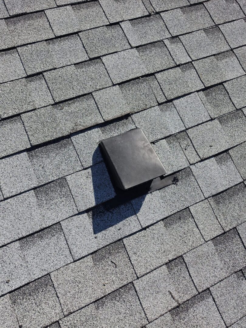 Newly installed roof vent on shingle roof